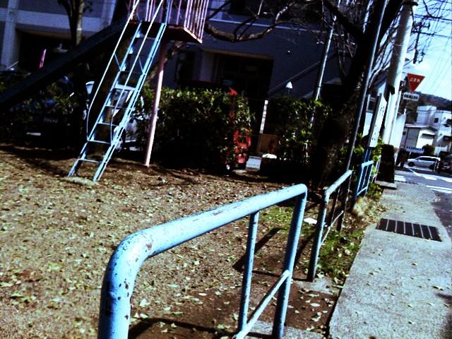 a street with a small house and a blue pipe going up some stairs