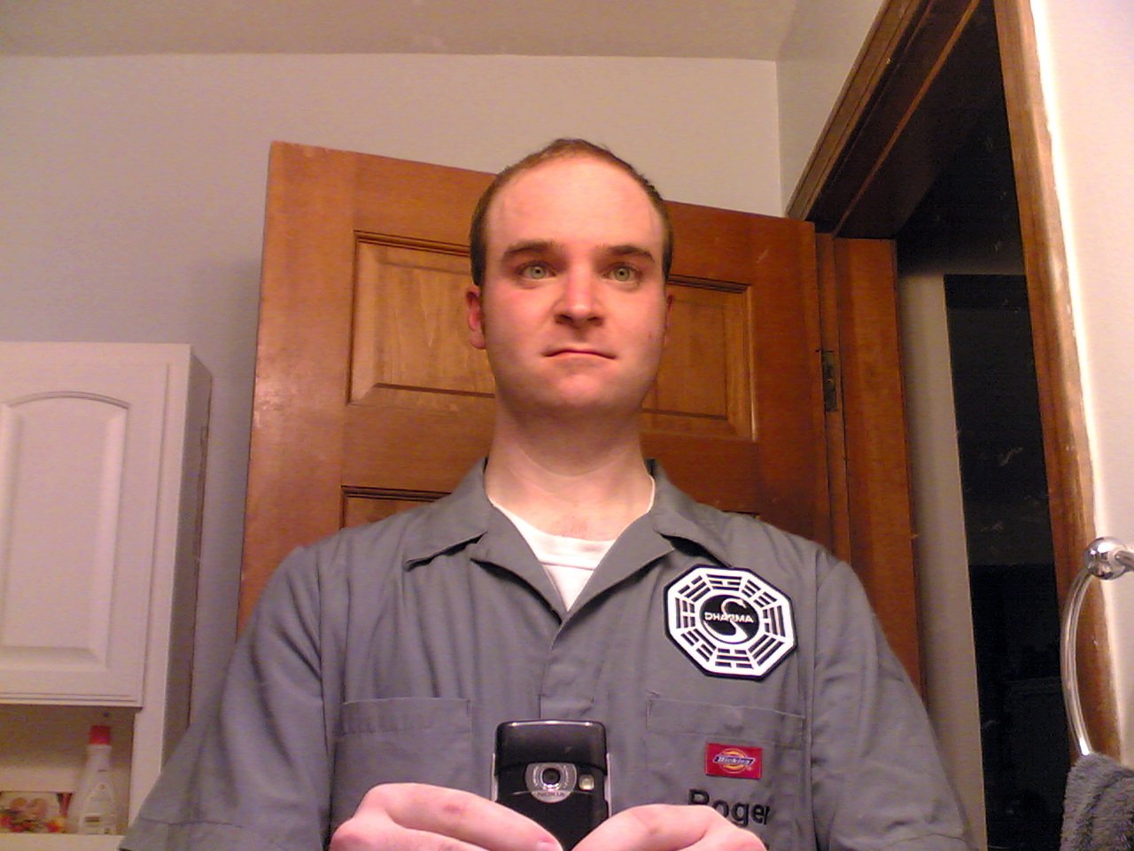 a man holding a smart phone wearing a frisbee badge