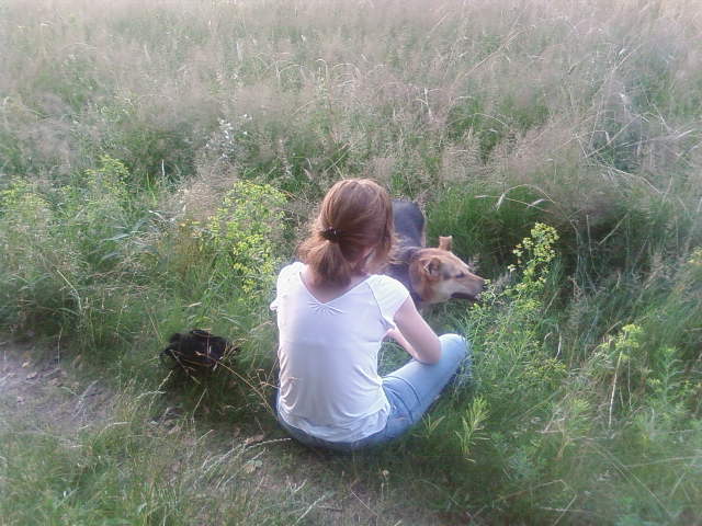 a girl sits in the grass with her dog