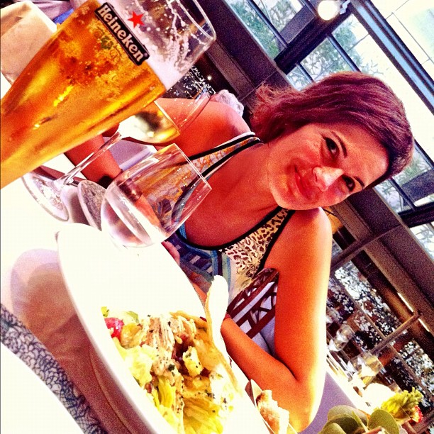 a woman sitting at a table with plates and glasses of beer