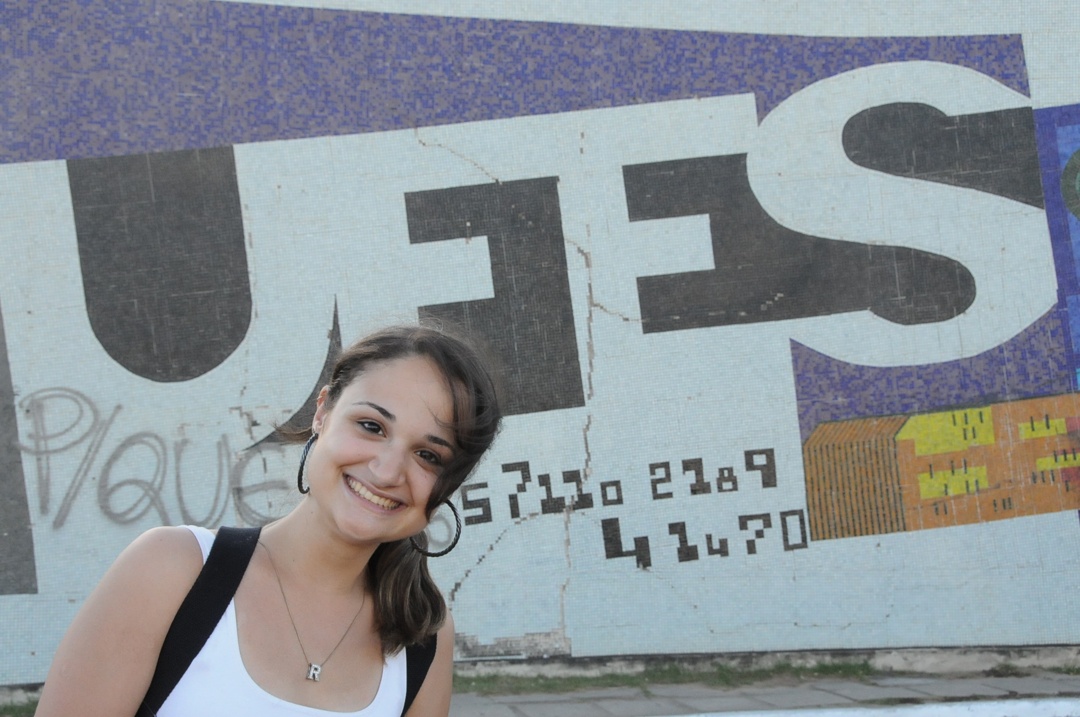 a young woman is posing in front of a graffiti - covered building