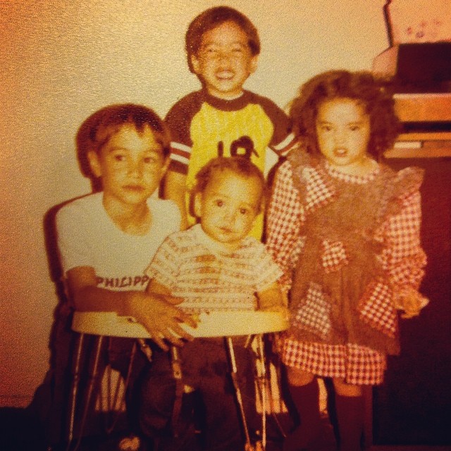 three children are posing with one of the two children on the stool