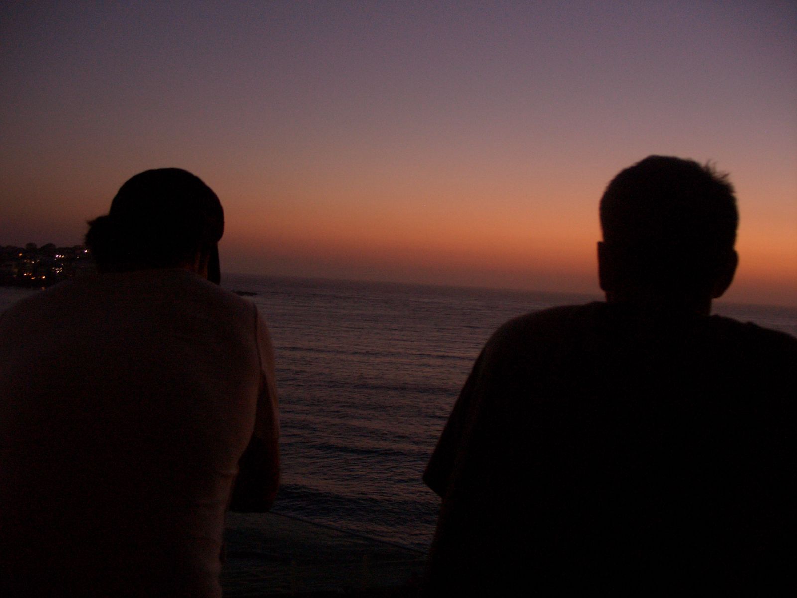 a man and a woman watch the sunset over the water