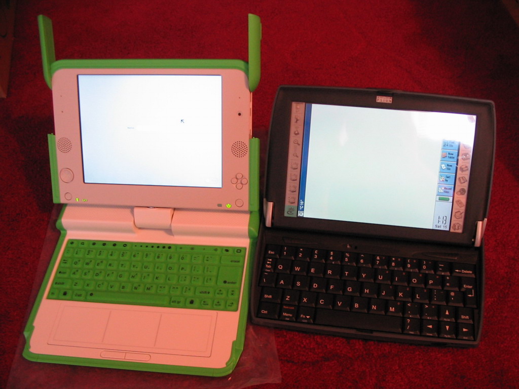a little green and white laptop next to an older black and white computer