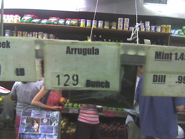 several people standing in a grocery store with two hanging labels for different nds