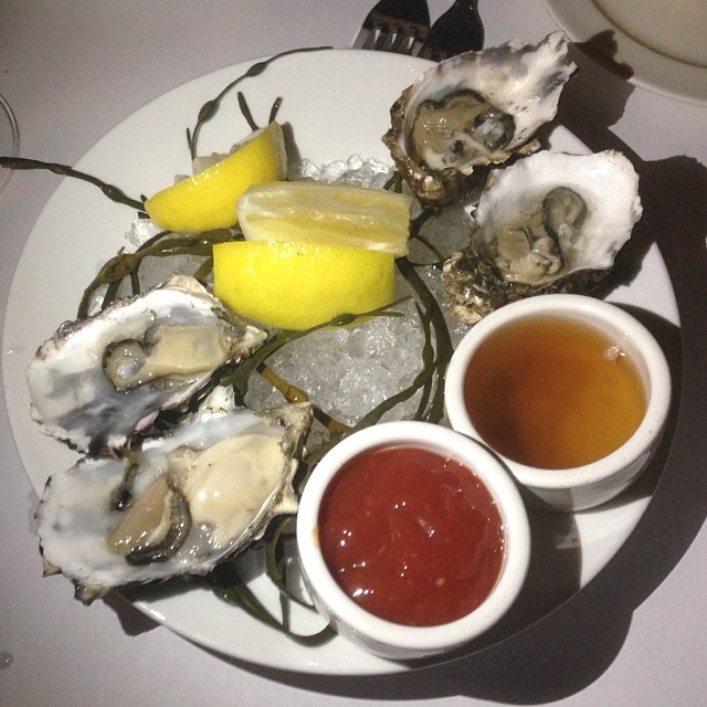 several oysters on the plate with lemon slices, ketchup and er