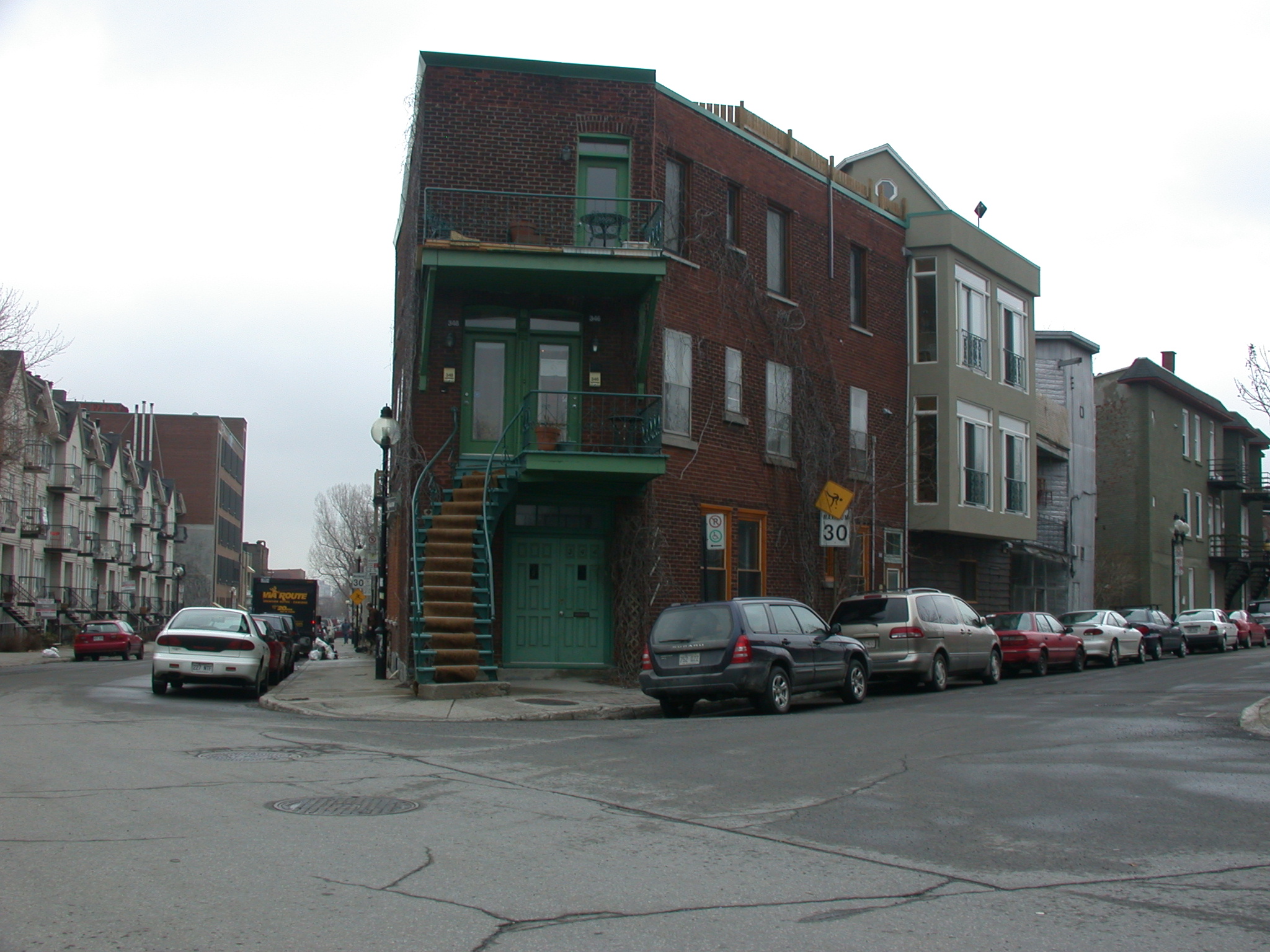 some parked cars are outside of some brick buildings