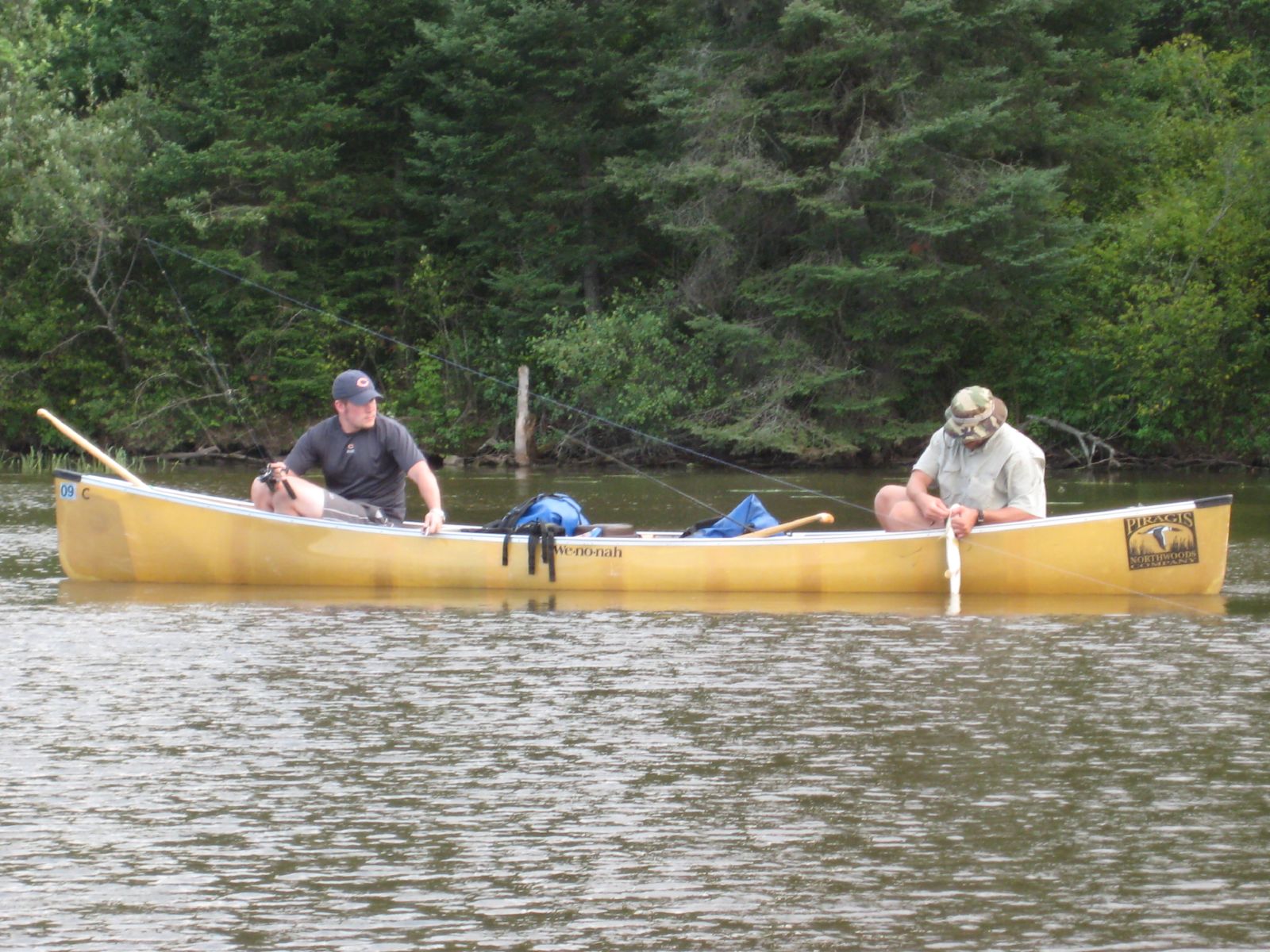 two people sitting in a yellow canoe on the river