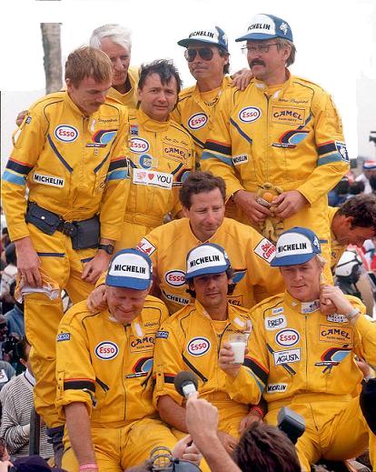 men in yellow race suits and blue hats drinking beer