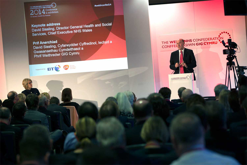 a man speaking at a podium in front of a large group