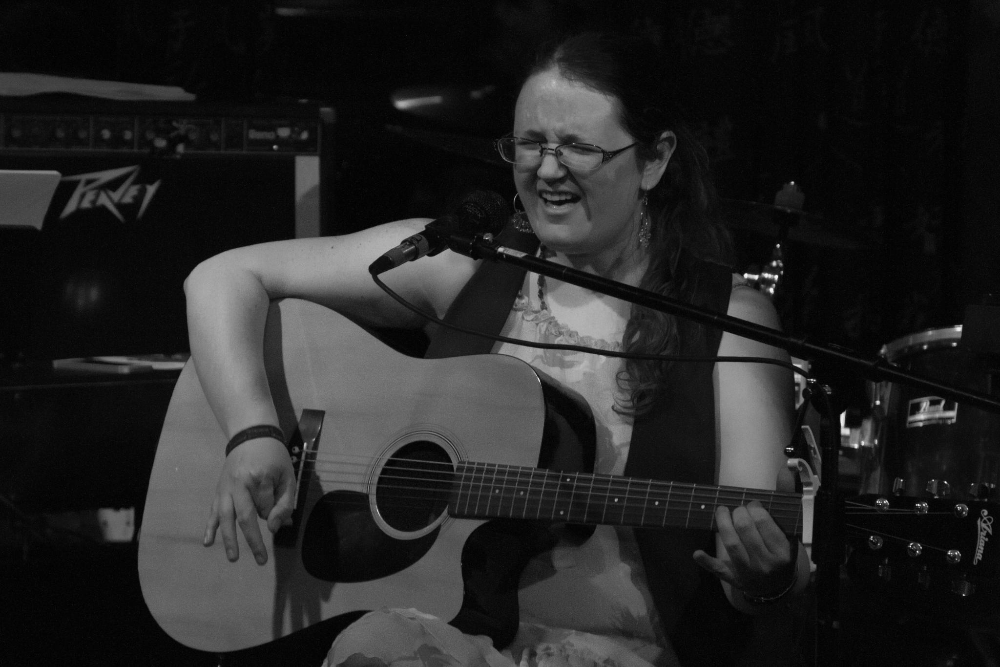 a woman holding an acoustic guitar on stage