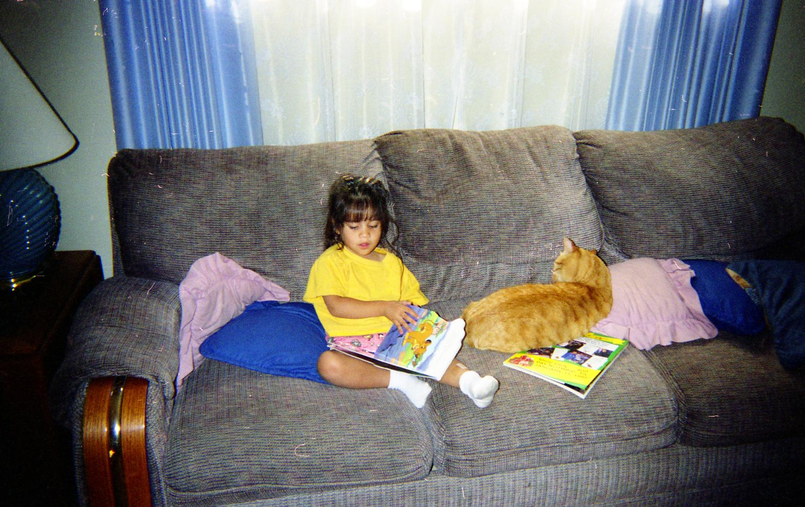 a girl and her cat reading on a couch