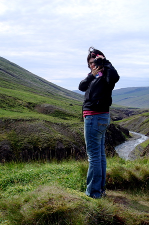 a person stands in a grassy valley near some hills