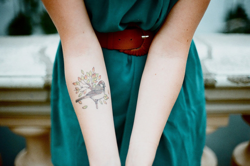 a girl has a bird tattoo on her left forearm