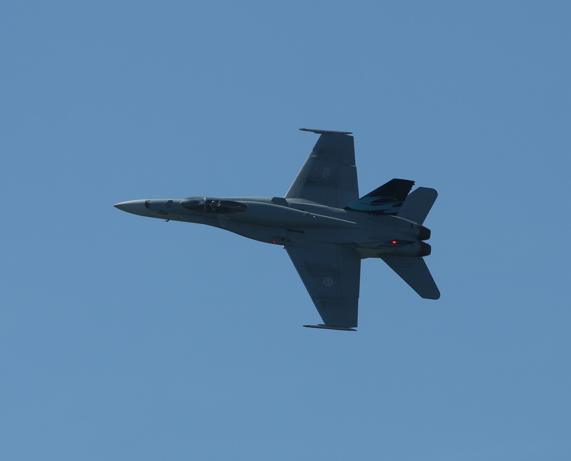 a military plane flying against a clear blue sky