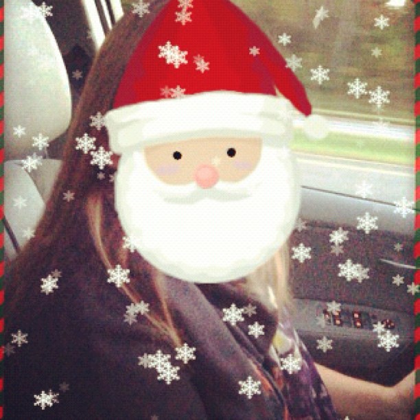 a woman driving a car with a santa clause face on