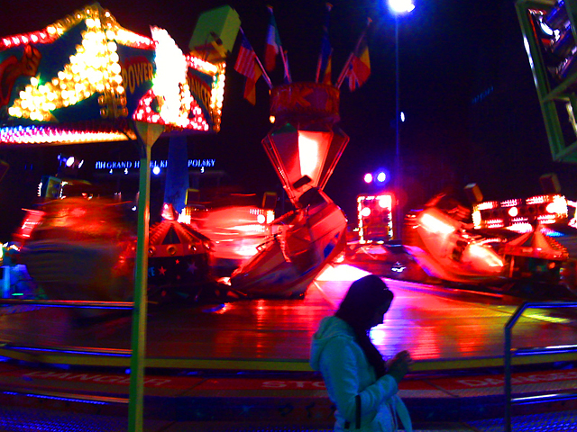 a person walking near an illuminated carnival ride