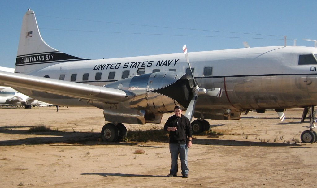 a man standing next to an airplane parked in dirt