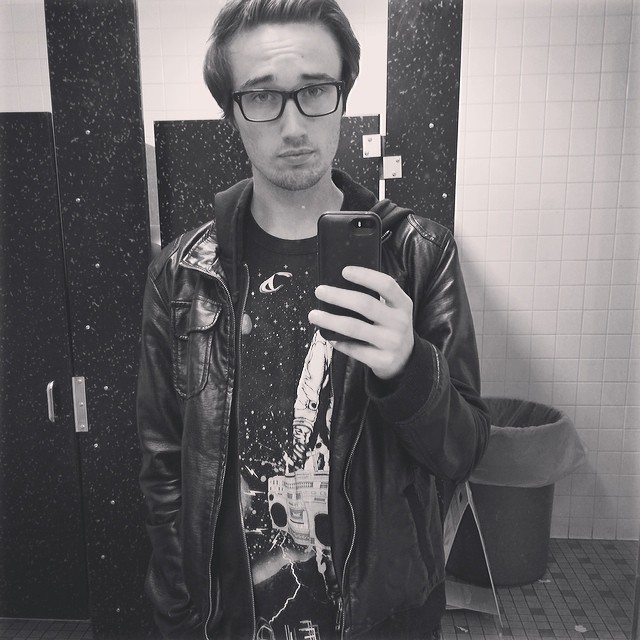 a man in a black jacket and glasses taking a selfie