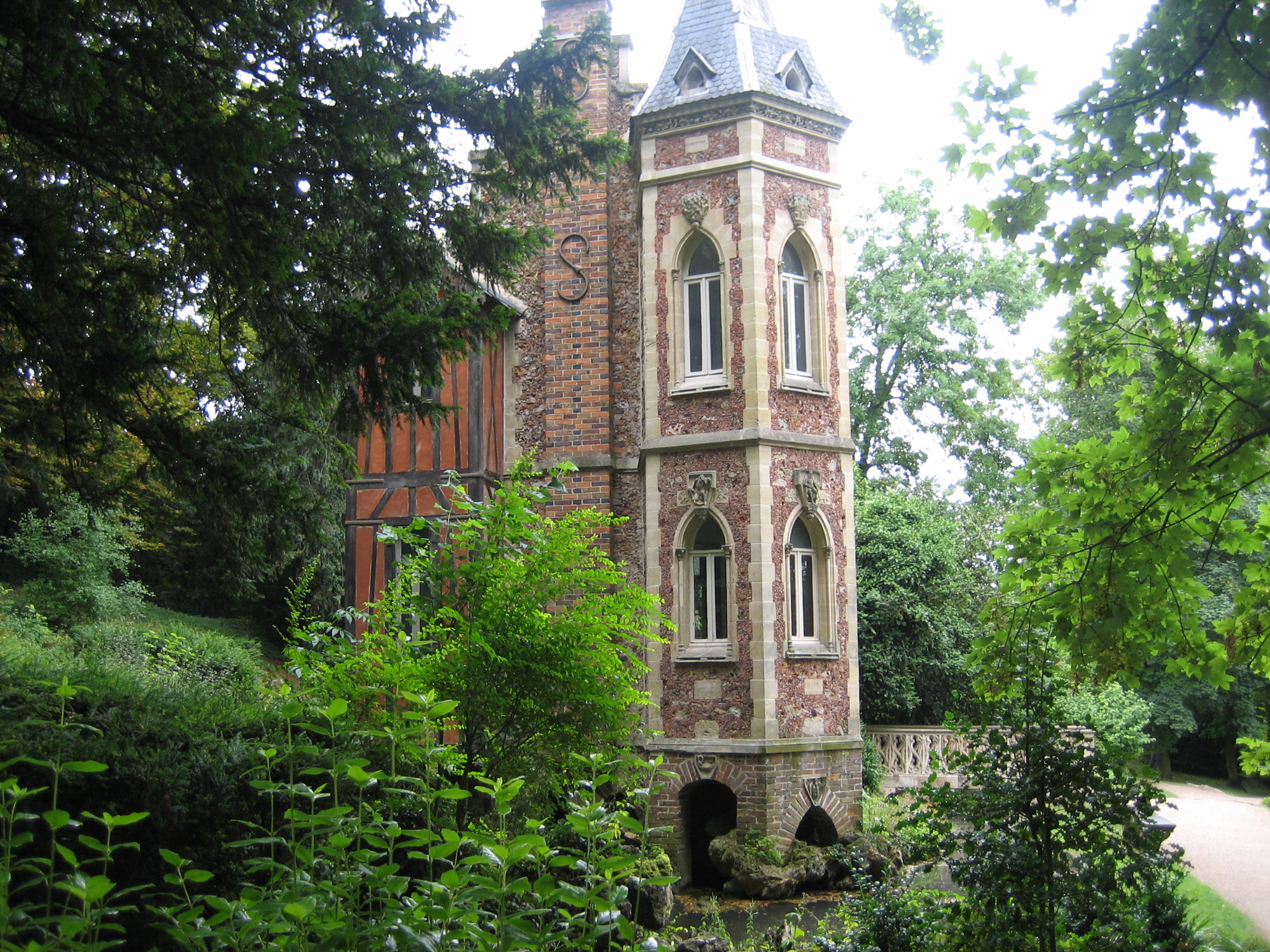 a tall brick clock tower sitting next to green trees