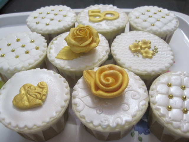 a dozen cupcakes with decorations on them, all decorated in white and gold