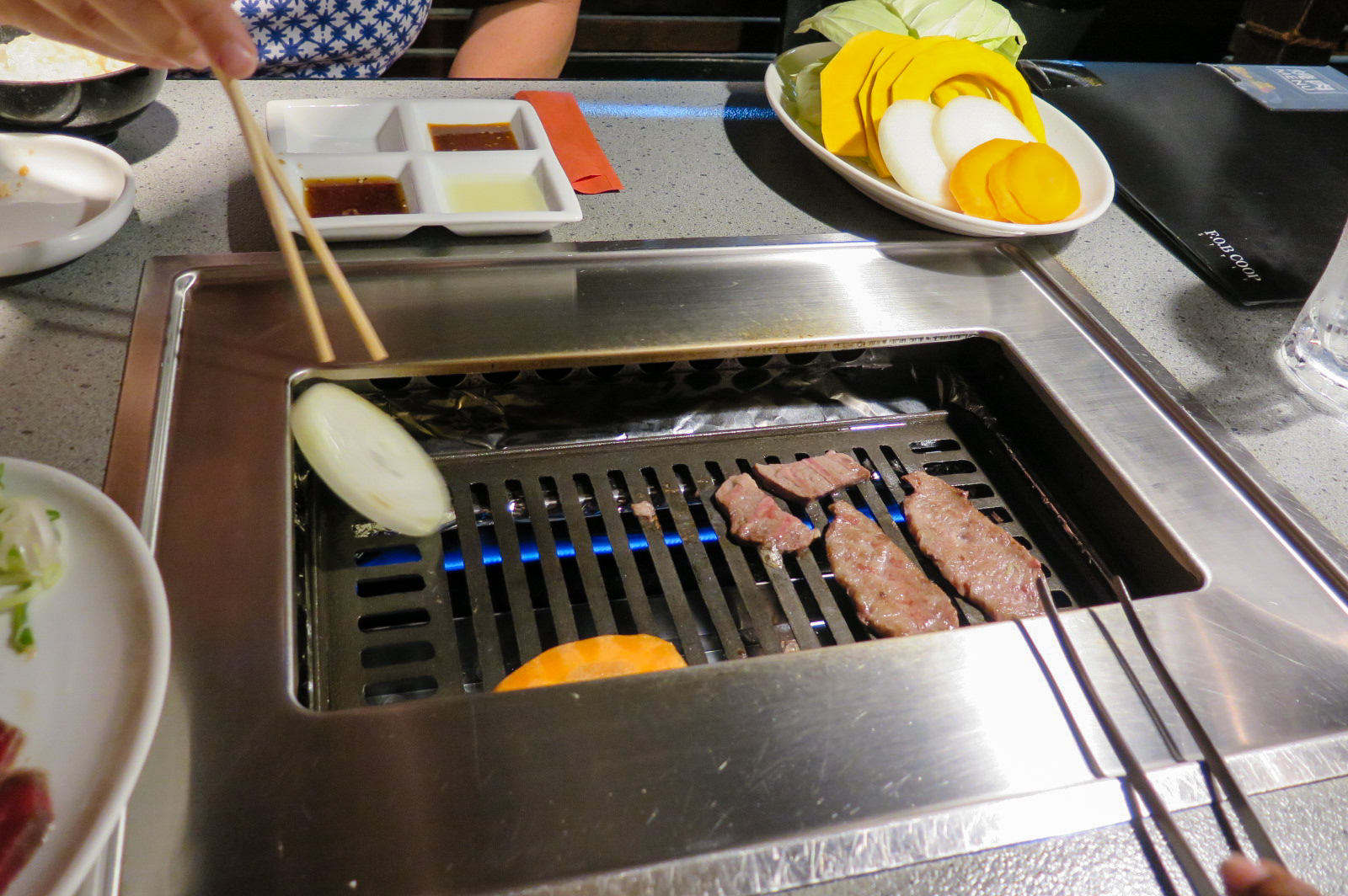 a person cooking some meat with chop sticks