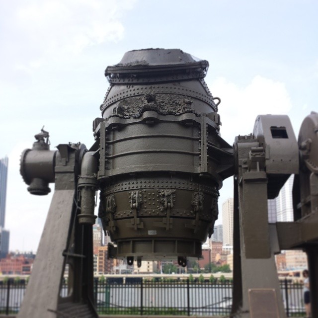 a large metal machine sitting next to a city skyline