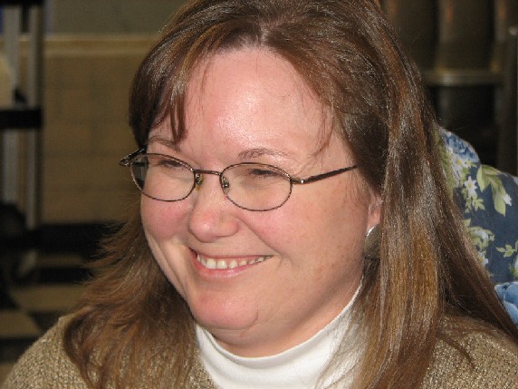 a woman is smiling at the camera in front of some desk space