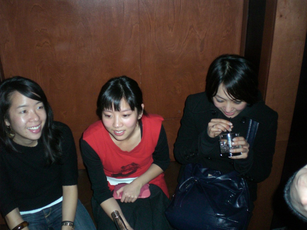 three women smile while looking at their cell phones