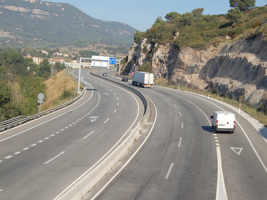 three lanes on road with vehicles travelling alongside the highway