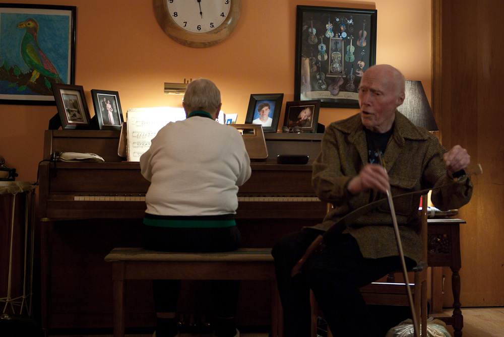 an old man sits in a chair next to a young woman