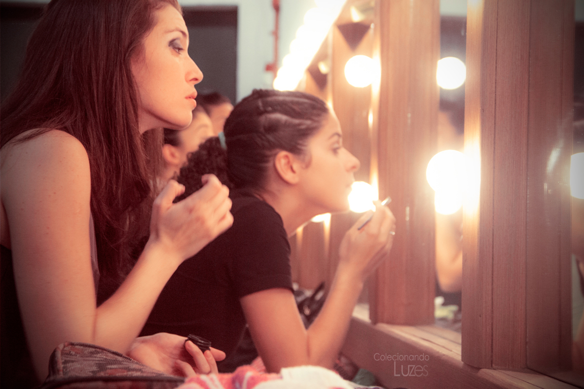 a woman getting her makeup applied in front of a mirror