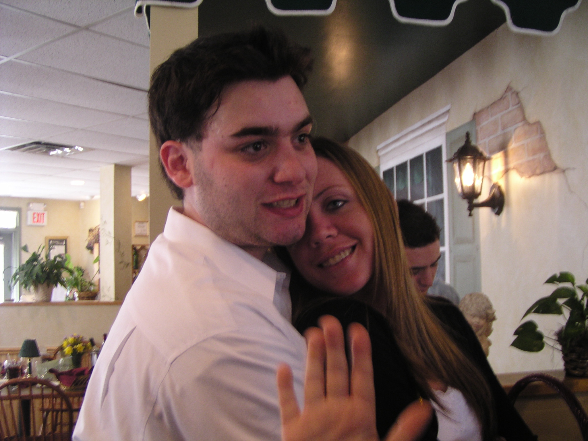 a woman hugging and giving the peace sign to a man