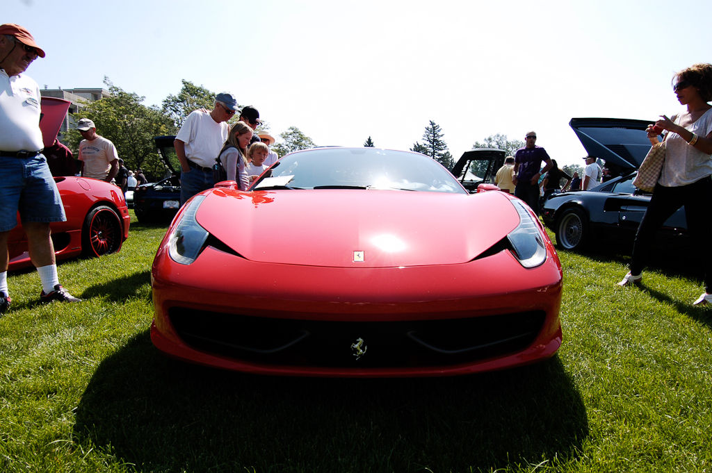 people standing around and admiring a red sports car