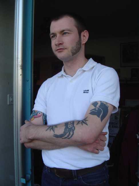 man with a tattoo standing by a door