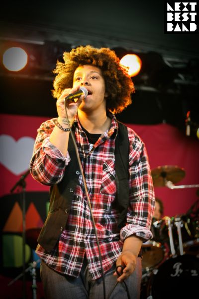 a young man with curly hair is singing into a microphone