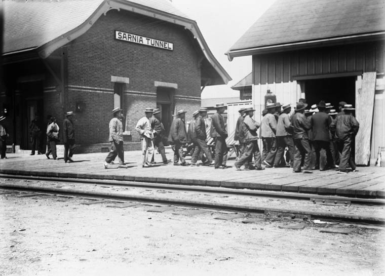 a group of men walk past a building with the door open