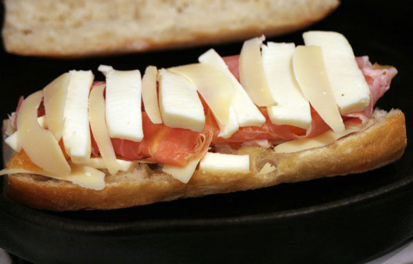 an open faced sandwich with cheese and tomato
