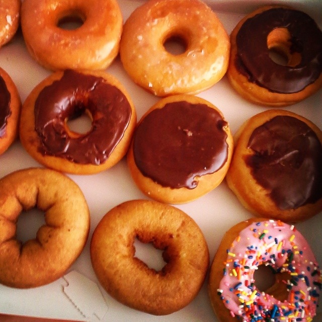 a box full of donuts with chocolate icing and sprinkles