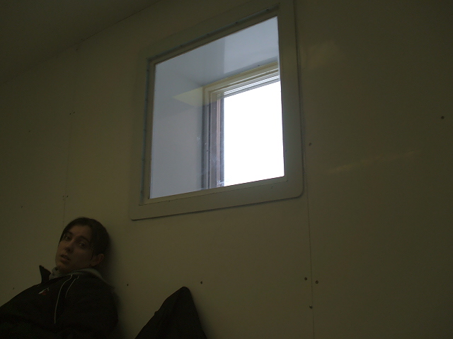a man sitting against a wall with a window above him