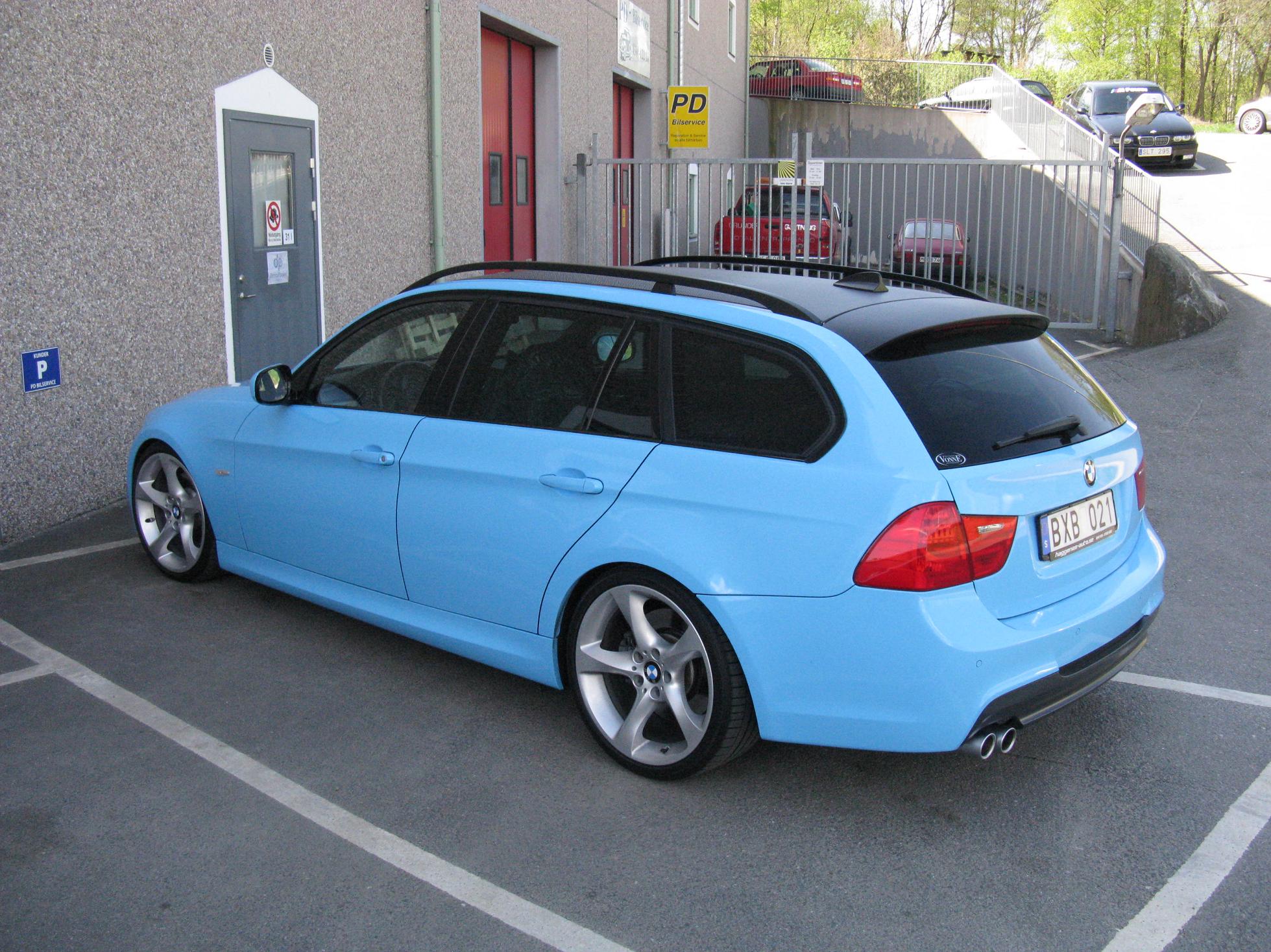 the back end of a blue bmw car in a parking lot