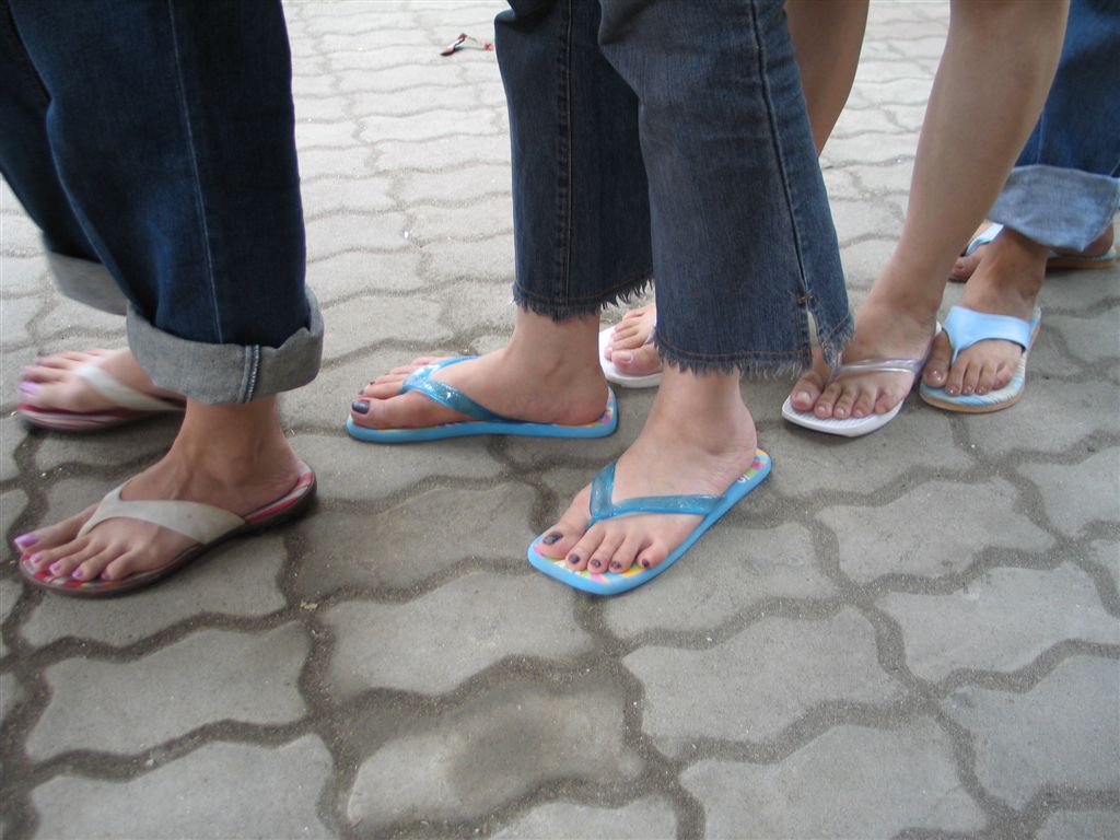 three pairs of people wearing flip flops with two woman with blue toes