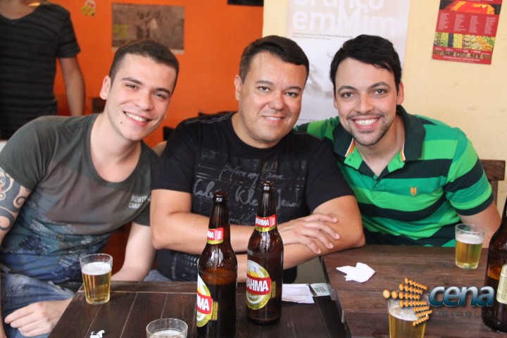 three men sitting at a table with some beer