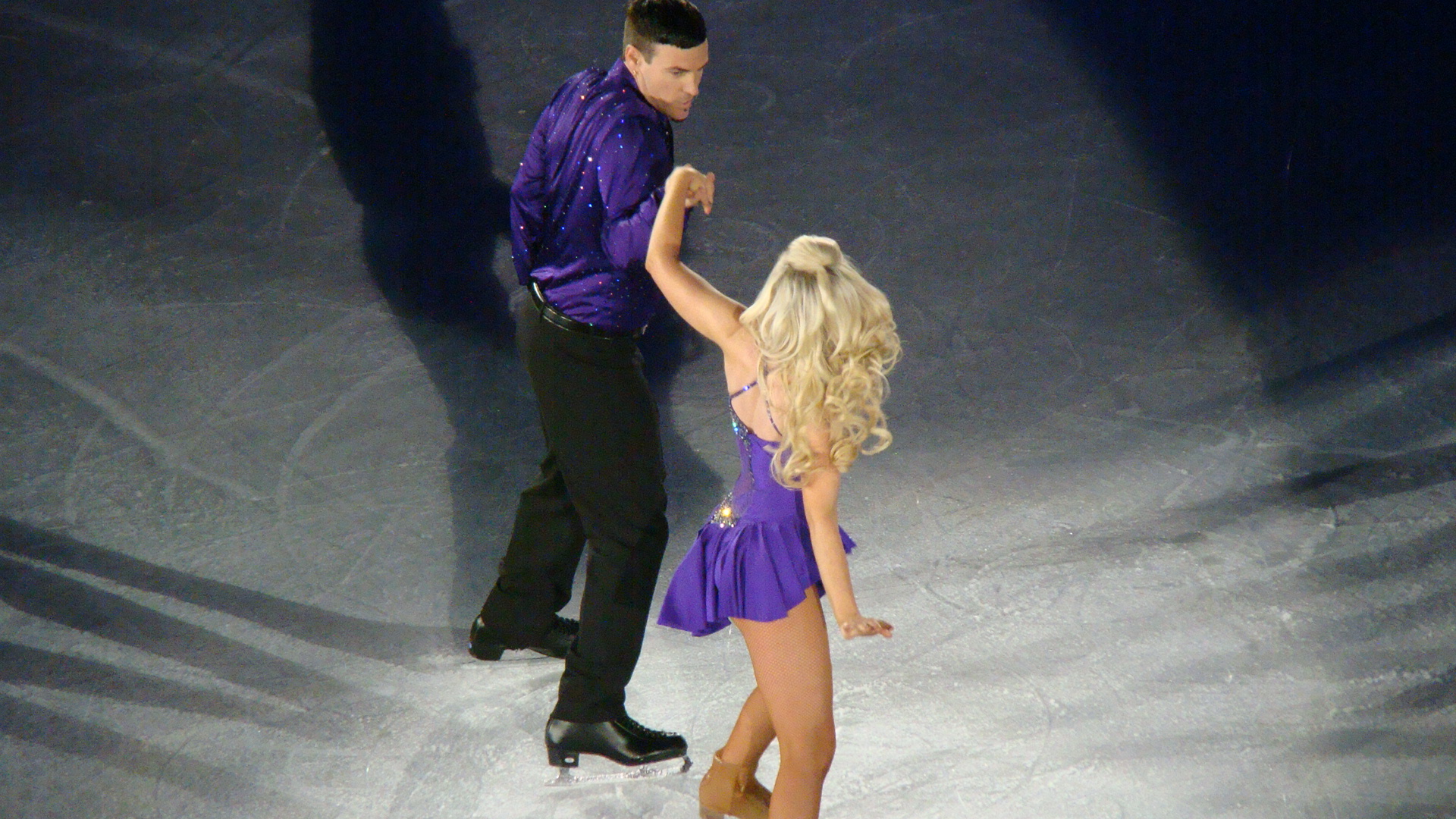 a woman and man are standing on top of an ice rink
