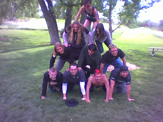 a group of girls sitting on top of a man in a park