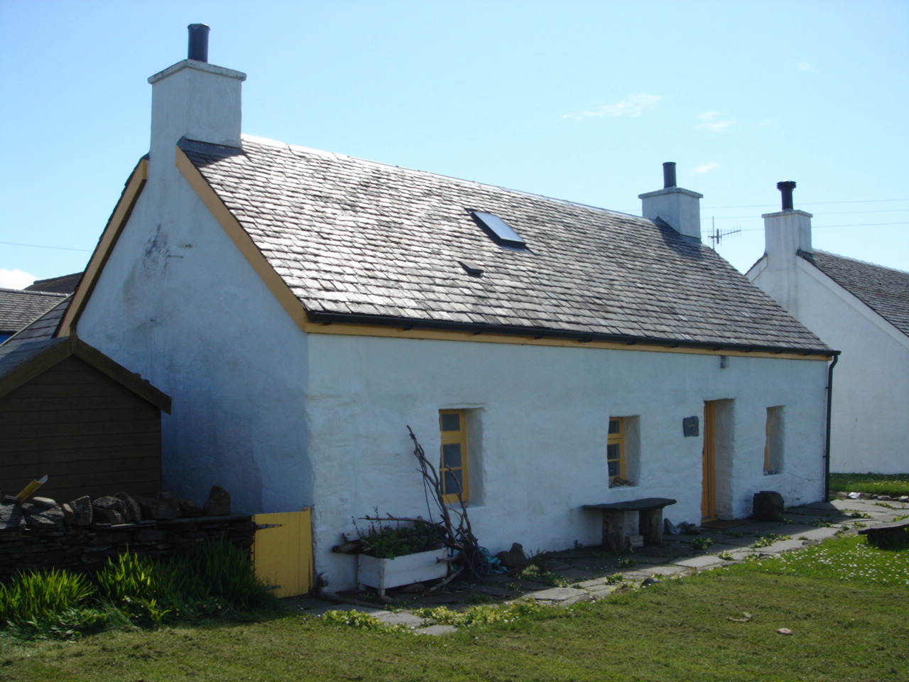 a white house with an attached shed with lots of windows