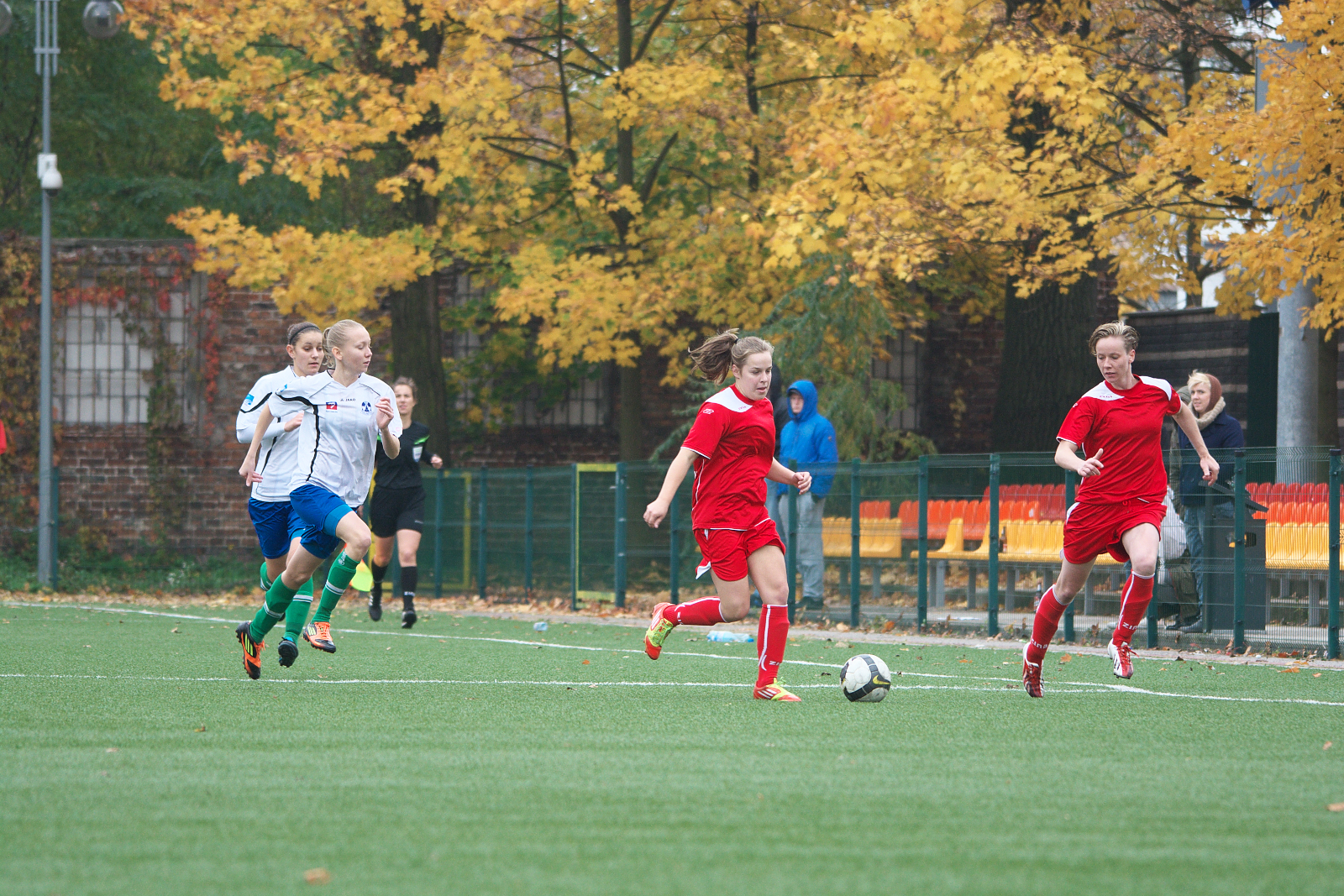 some female soccer players are running to kick the ball