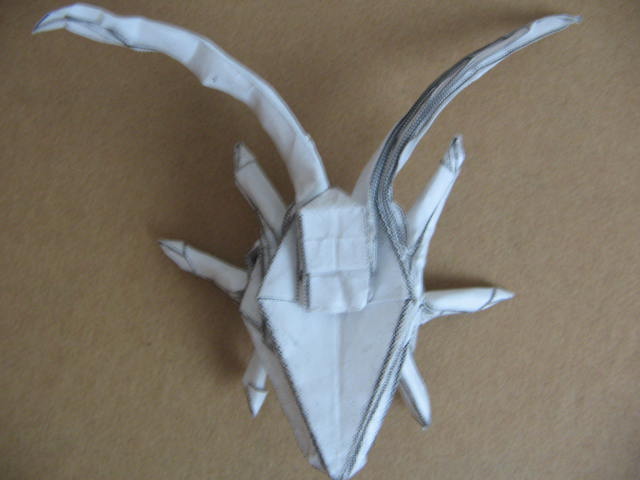 a white origami dragon on a brown background