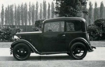 an old po of a black and white car in front of bushes