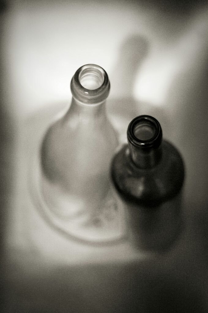 two empty wine bottles sitting in the middle of a sink